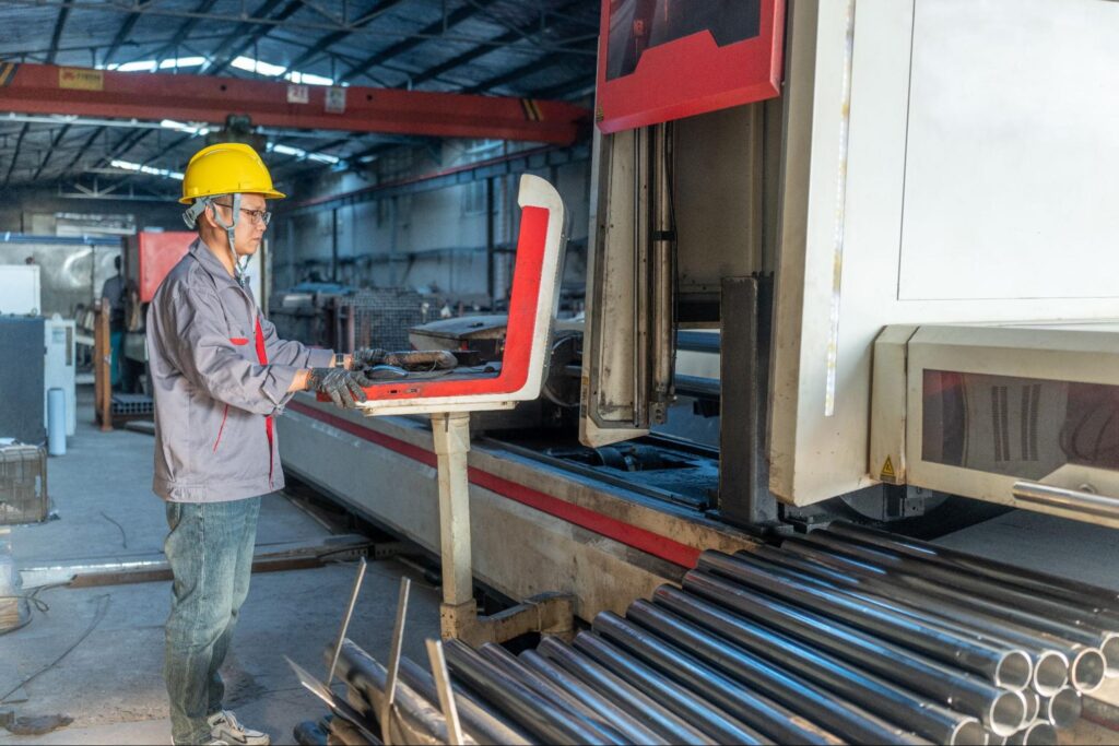 Factory worker wearing a yellow helmet operating a large industrial machine in Bunty LLC facility