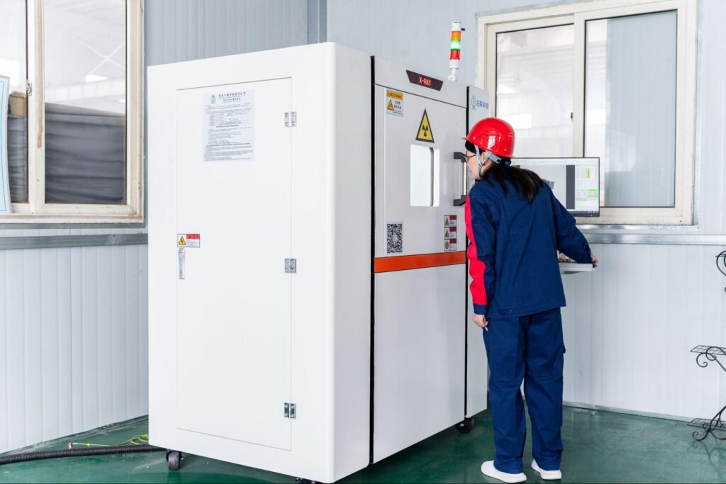 Female worker in safety gear operating an industrial X-ray inspection machine